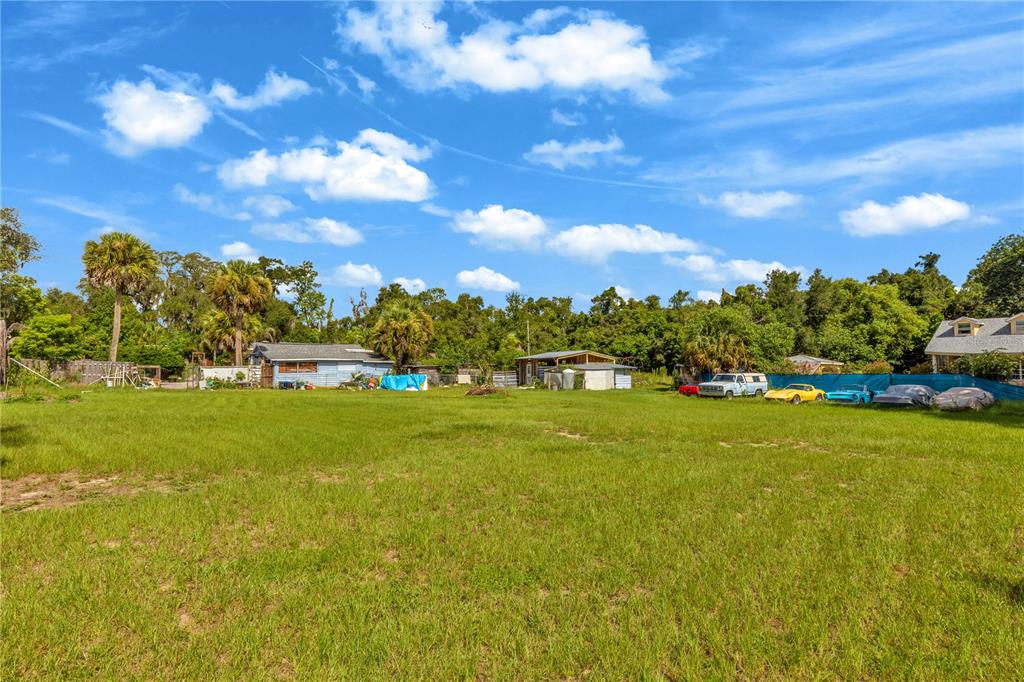 An aerial view shows a property with multiple buildings, a large grassy yard, and parked cars — 405 W SIMON AVENUE, APOPKA, FL