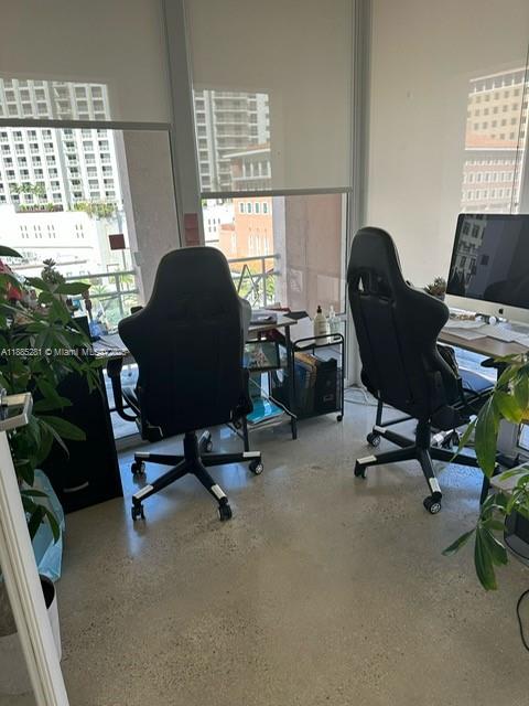 A home office features two black gaming chairs, desks, and large windows with city views — 95 Merrick Way # 710, Coral Gables FL 33134, CORAL GABLES, FL