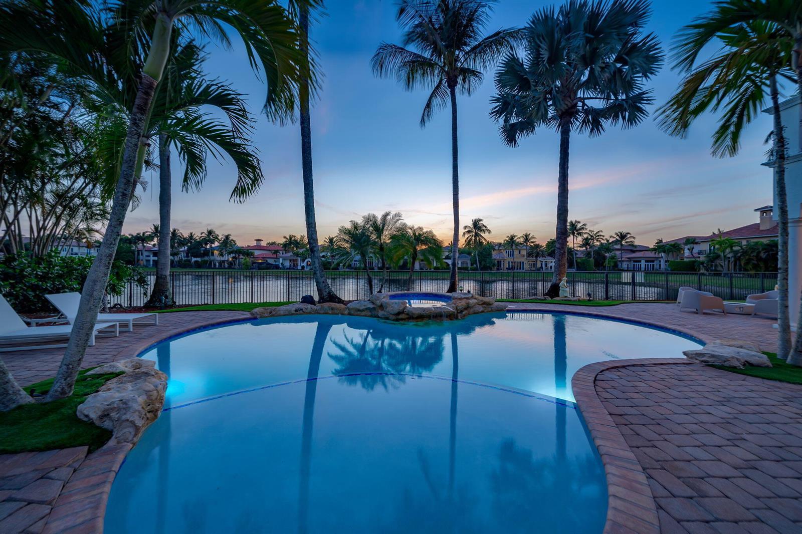 A swimming pool and hot tub overlook a lake surrounded by palm trees at dusk — 17593 Middle Lake Drive, Boca Raton FL 33496, BOCA RATON, FL