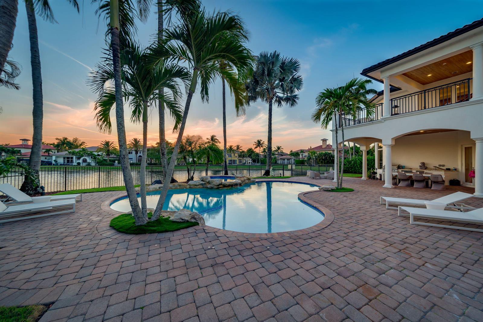A backyard patio features a swimming pool, palm trees, and a two-story house at sunset — 17593 Middle Lake Drive, Boca Raton FL 33496, BOCA RATON, FL