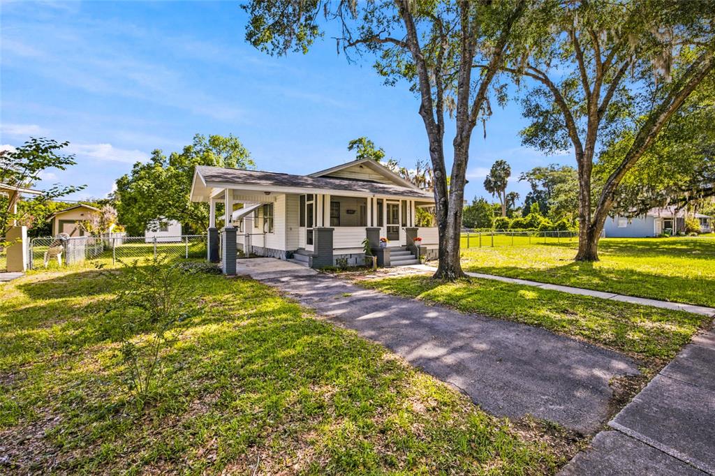 A single-story house with a front porch and carport sits on a grassy lot — 20315 THE GRANADA, DUNNELLON, FL