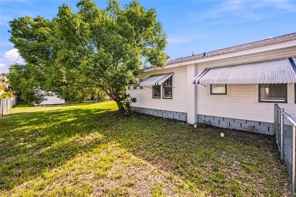 A white house with metal awnings stands next to a large tree in a yard — 20315 THE GRANADA, DUNNELLON, FL