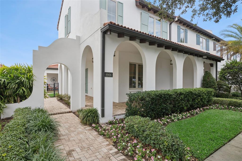 A white two-story house features a covered arched walkway and a brick paver path — 8866 BISMARCK PALM DRIVE, WINTER GARDEN, FL