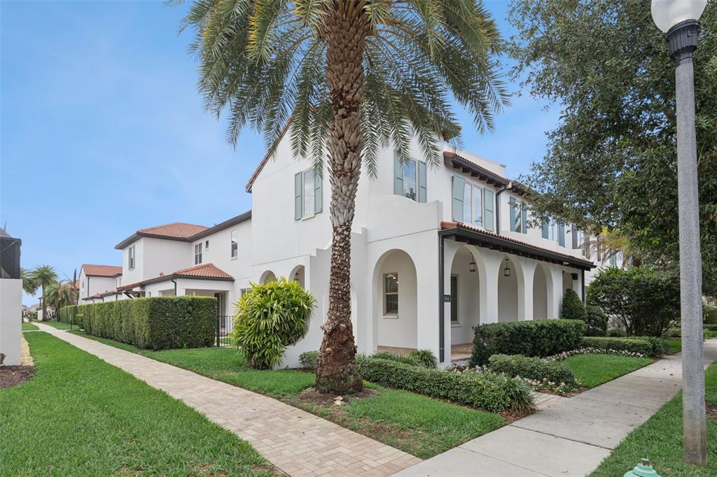 A white two-story townhouse with arched entryways, a palm tree, and a paved walkway — 8866 BISMARCK PALM DRIVE, WINTER GARDEN, FL