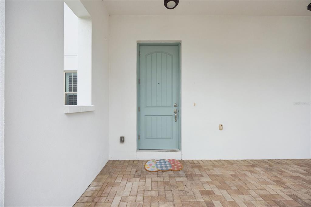 A light blue front door opens onto a covered porch with paved flooring — 8866 BISMARCK PALM DRIVE, WINTER GARDEN, FL