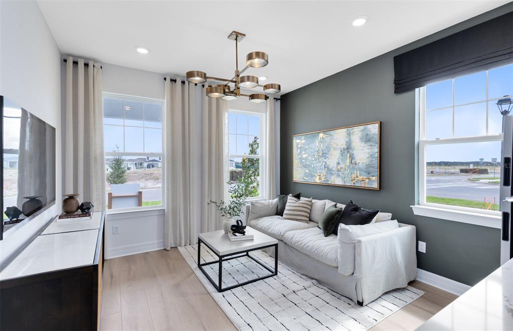 A living room features a gray accent wall, a white sofa, and a modern chandelier — 2627 CLEAR NIGHT AVENUE, KISSIMMEE, FL