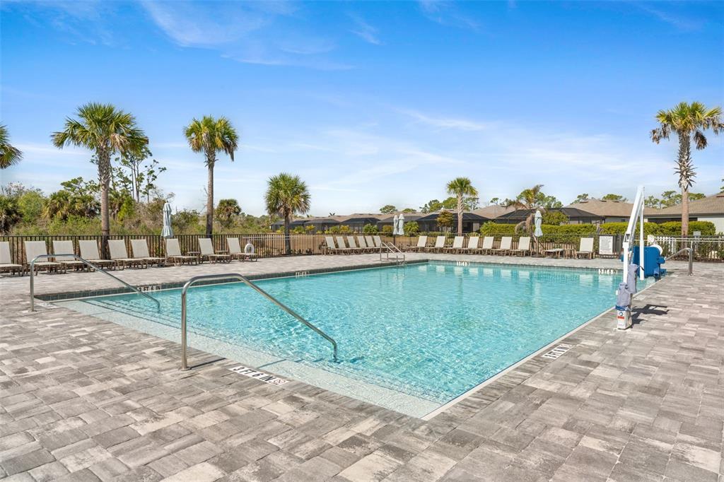 A rectangular swimming pool is surrounded by a paved deck with lounge chairs and palm trees — 1536 SADDLEWOOD CIRCLE, PORT CHARLOTTE, FL