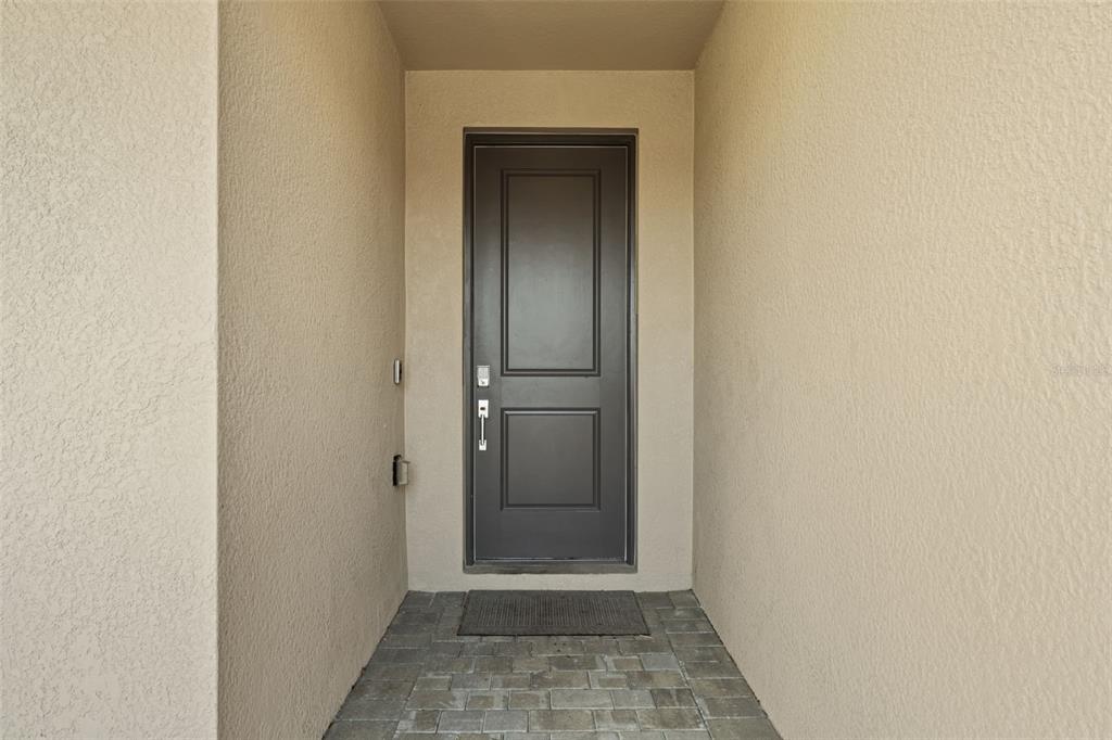 A dark gray front door is centered in a recessed entryway with beige stucco walls — 1536 SADDLEWOOD CIRCLE, PORT CHARLOTTE, FL