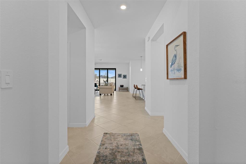 A bright hallway with tile flooring leads to an open-concept living area and kitchen — 1536 SADDLEWOOD CIRCLE, PORT CHARLOTTE, FL