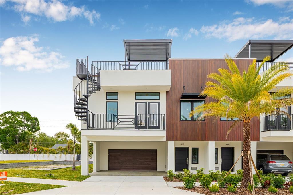 A modern multi-story townhouse exterior features a spiral staircase, balconies, and a ground-level garage — 484 87TH AVENUE NORTH, ST PETERSBURG, FL