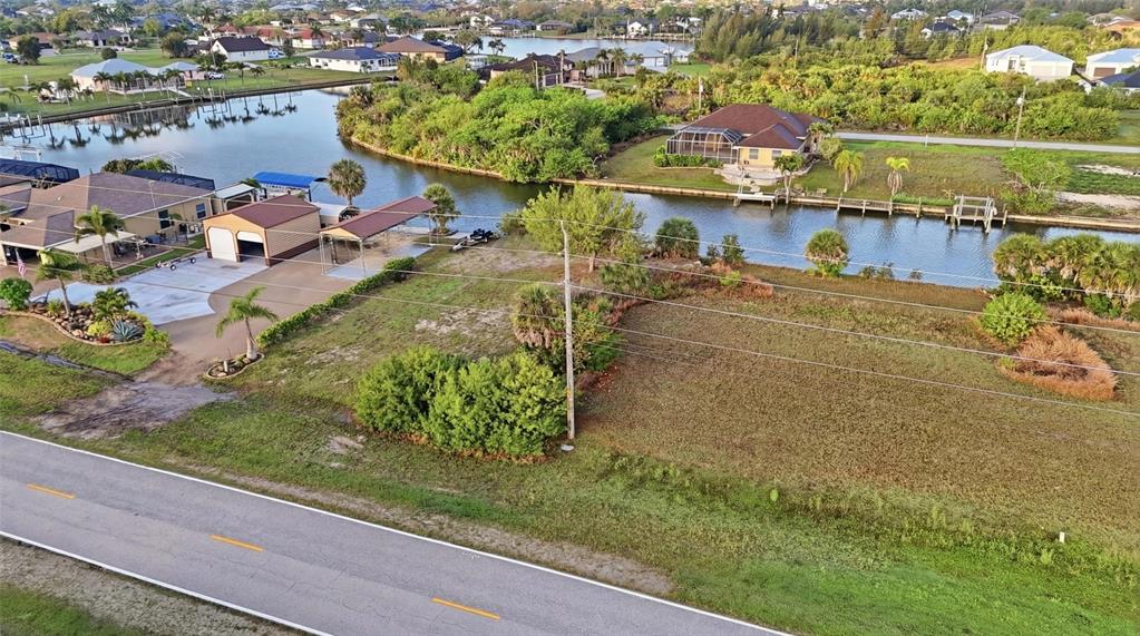 An aerial view shows a vacant waterfront lot next to a house with a garage — 8869 ST PAUL DRIVE, PORT CHARLOTTE, FL