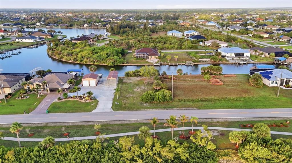 An aerial view shows a vacant waterfront lot next to a house with a garage — 8869 ST PAUL DRIVE, PORT CHARLOTTE, FL
