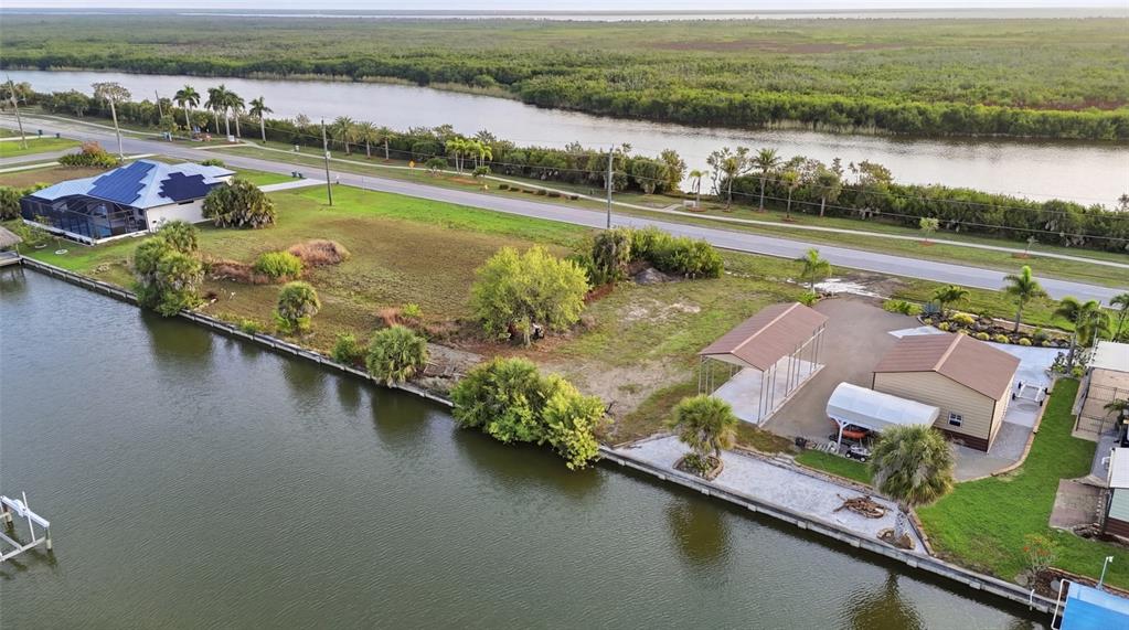 An aerial view shows a waterfront lot with a garage, carport, and adjacent house — 8869 ST PAUL DRIVE, PORT CHARLOTTE, FL