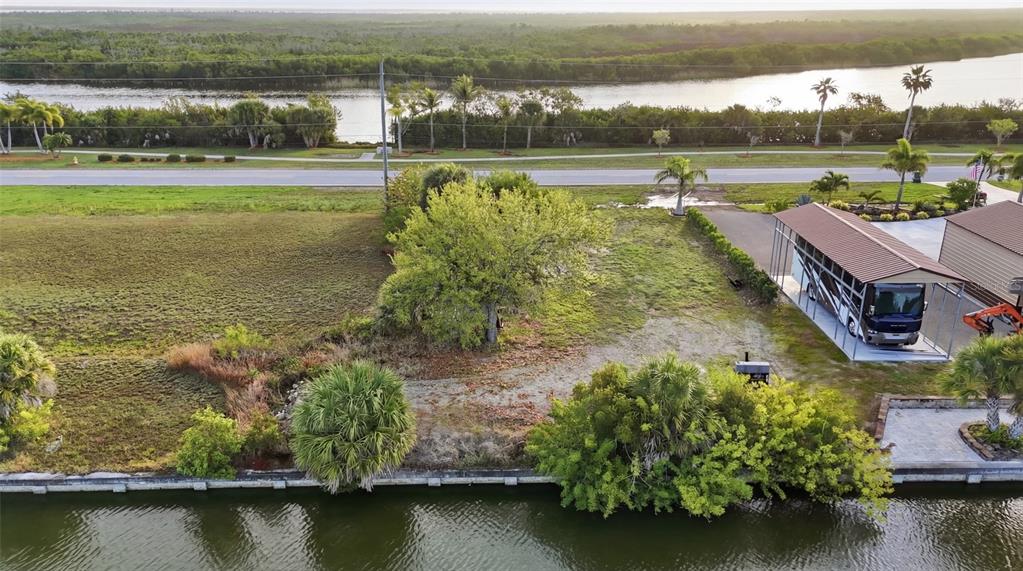 An aerial view of a waterfront lot featuring a large tree, vegetation, and a carport — 8869 ST PAUL DRIVE, PORT CHARLOTTE, FL