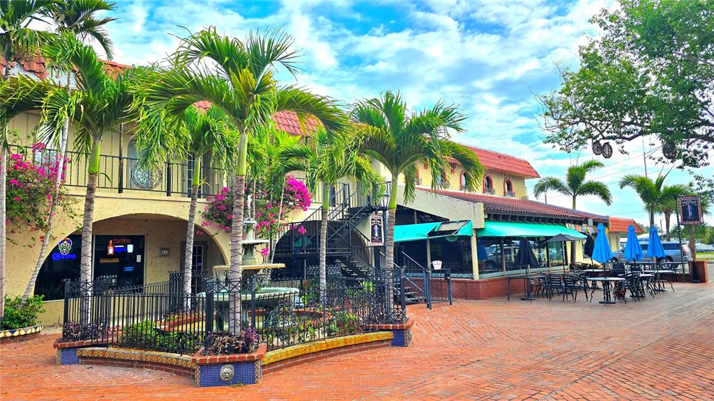 A two-story building with a brick patio, a central fountain, and palm trees — 530 US-41-BYP UNIT 17 and 18A, VENICE, FL
