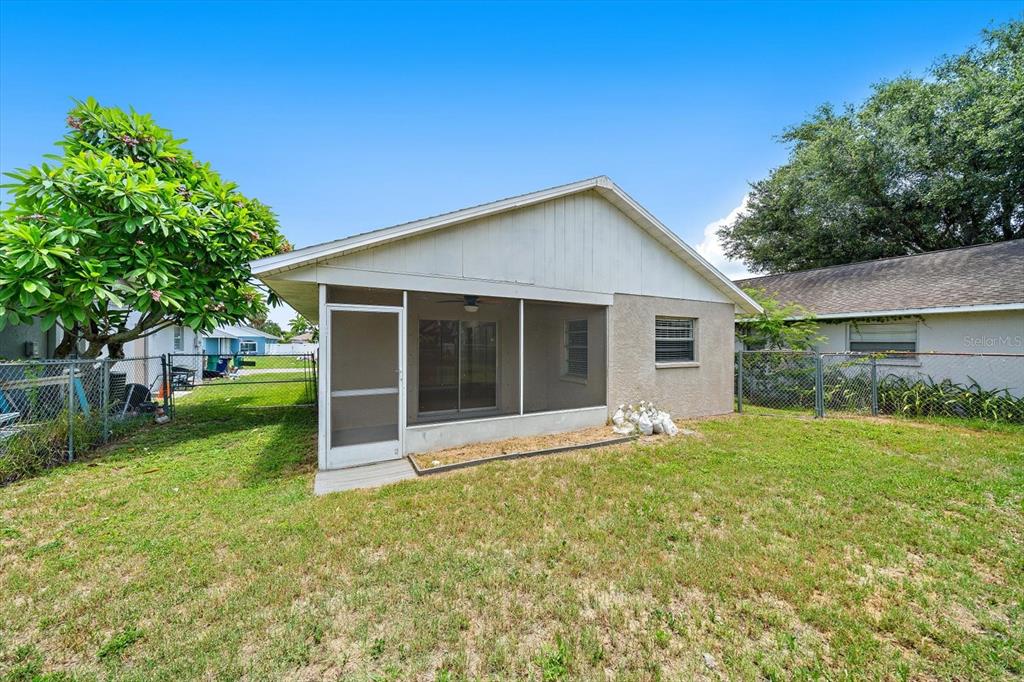 A backyard view of a house with a screened-in porch and a chain-link fence — 1521 13TH STREET W, PALMETTO, FL