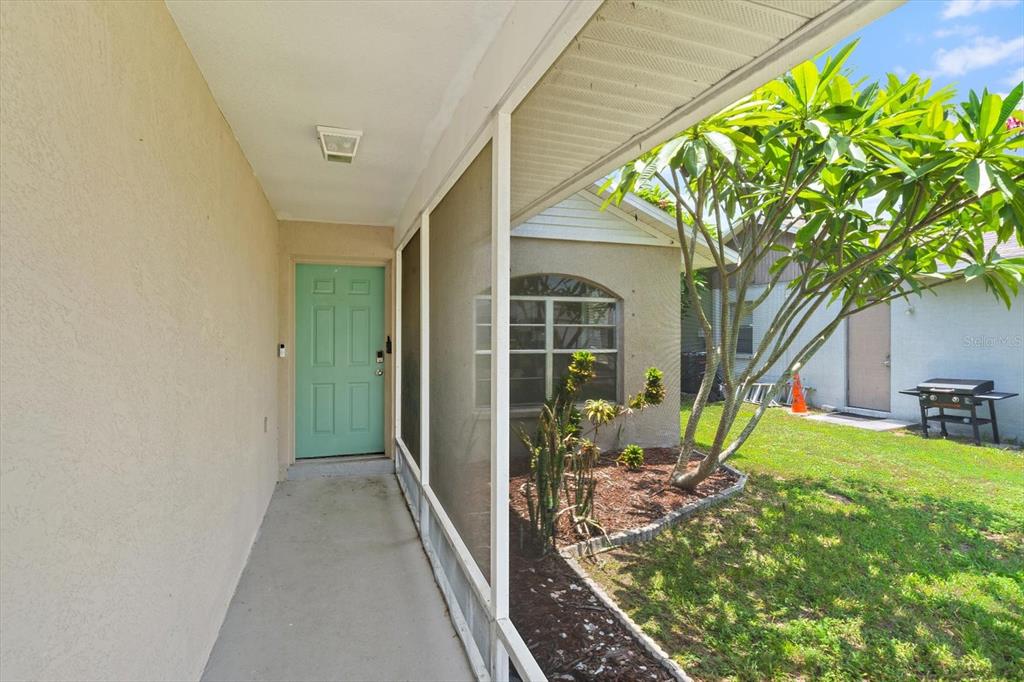 A covered porch with a screened enclosure leads to a light green front door — 1521 13TH STREET W, PALMETTO, FL