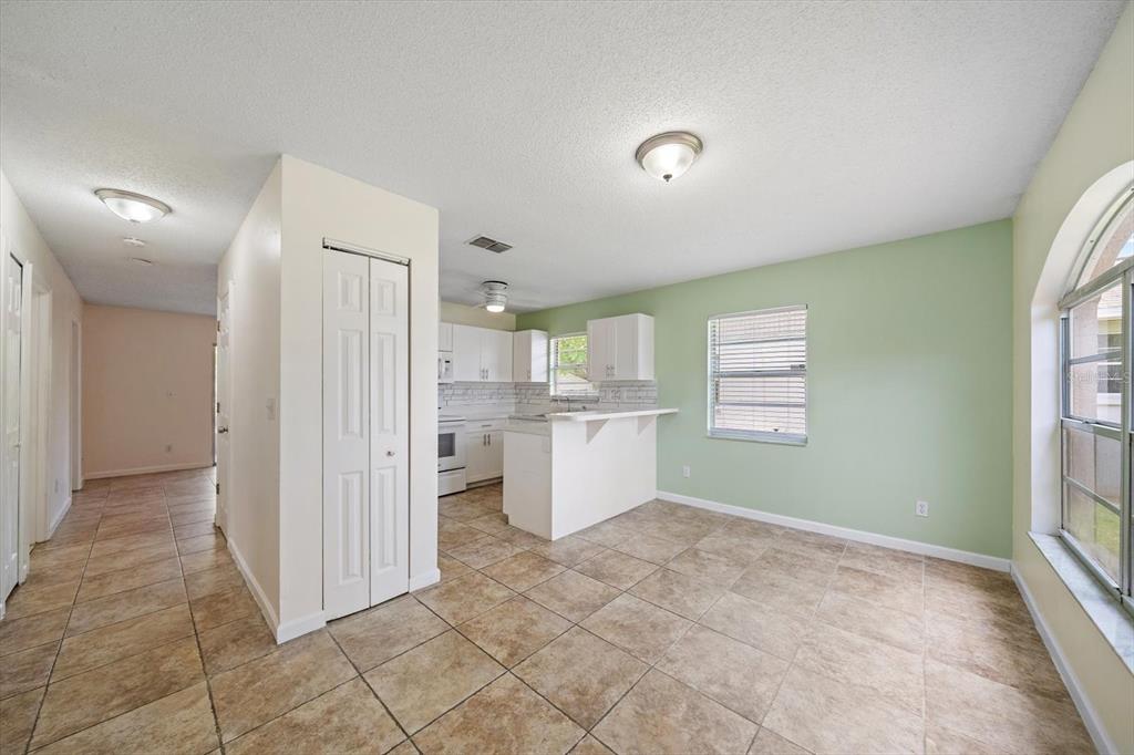 A kitchen with white cabinets and a breakfast bar opens into a tiled dining area — 1521 13TH STREET W, PALMETTO, FL
