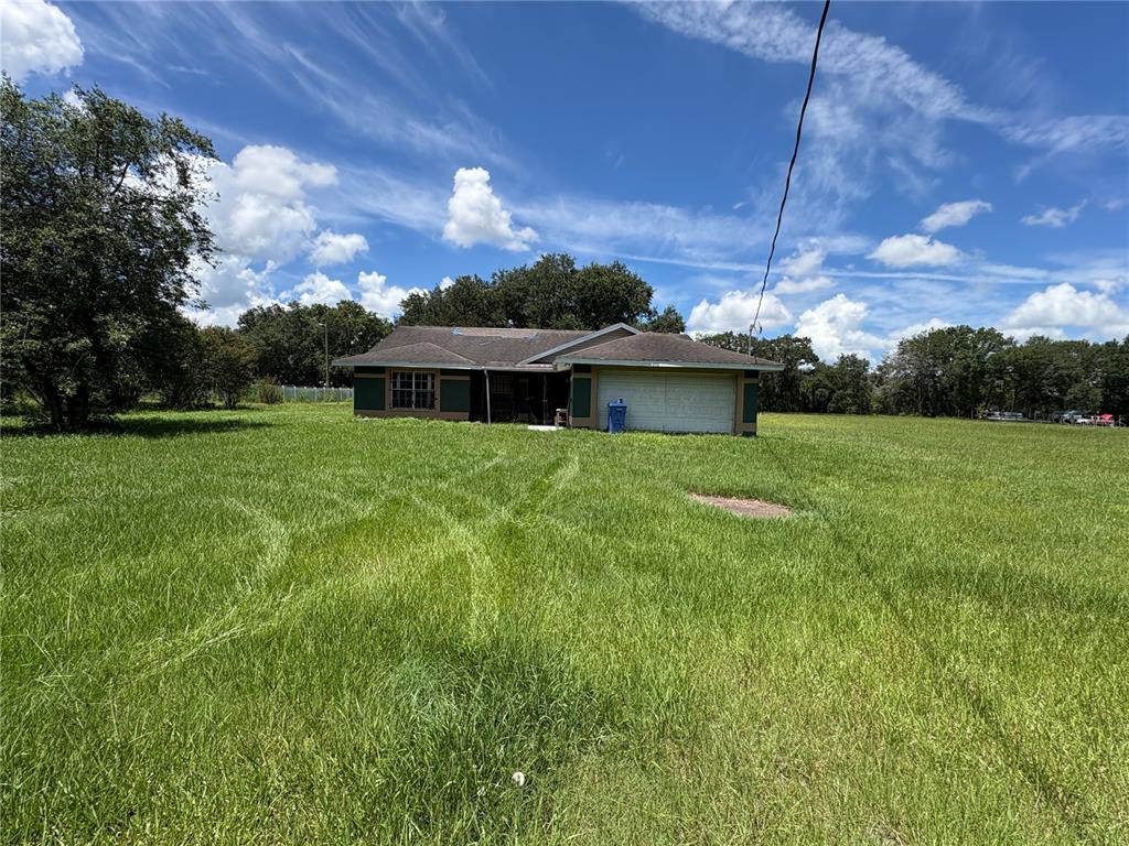 A single-story house with a garage sits in the middle of a large, grassy field — 4951 JOHN WESLEY PLACE, PLANT CITY, FL