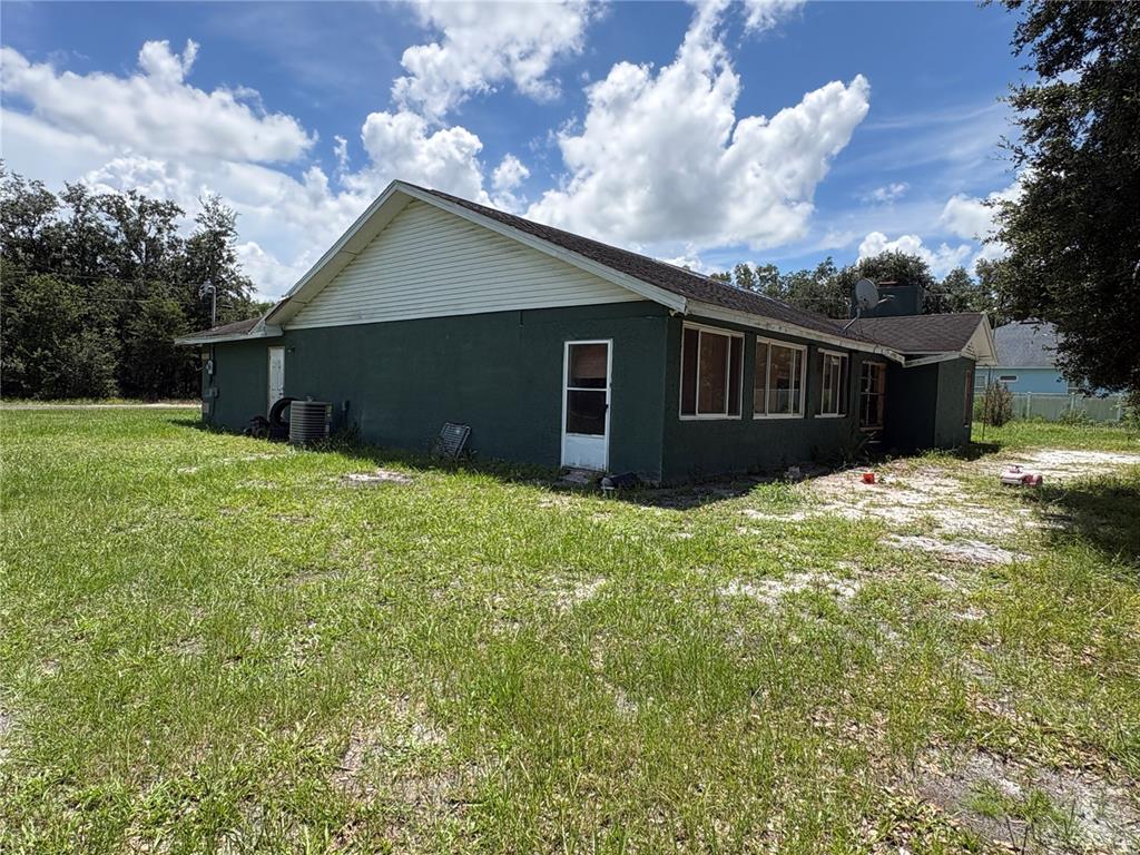The exterior of a dark green, single-story house with a white door and several windows — 4951 JOHN WESLEY PLACE, PLANT CITY, FL
