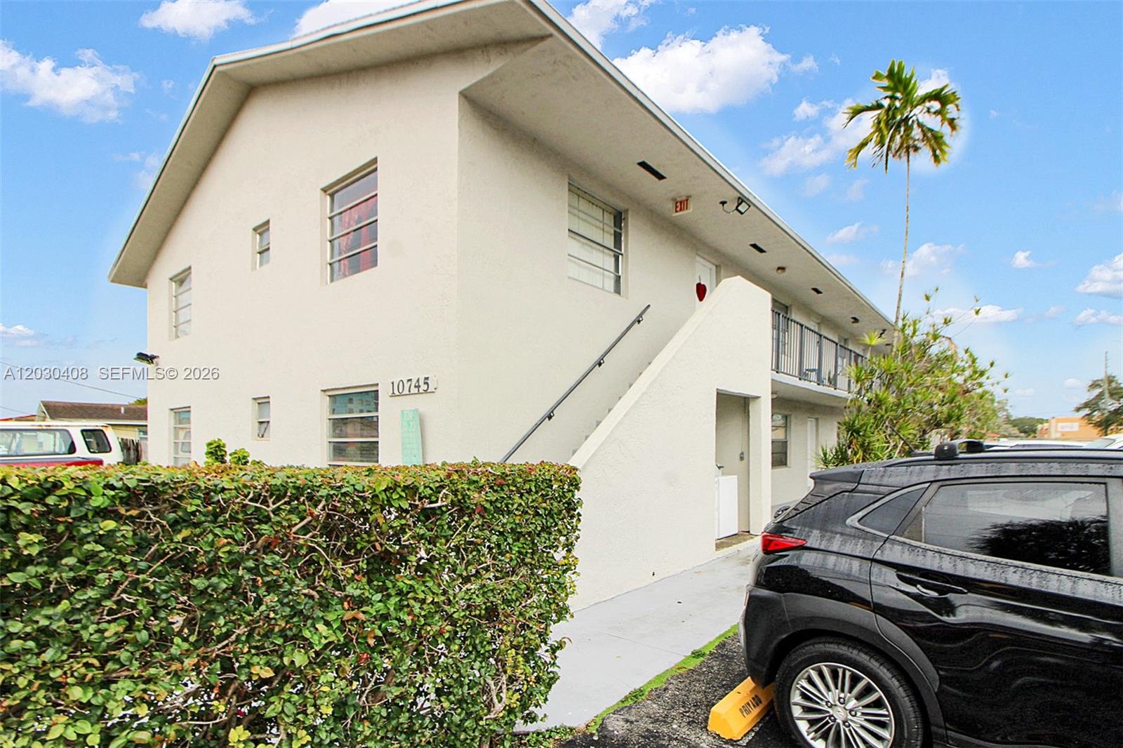 A two-story apartment building exterior features a concrete staircase, a hedge, and a parked car — 10745 SW 3rd St # 6, Sweetwater FL 33174, SWEETWATER, FL