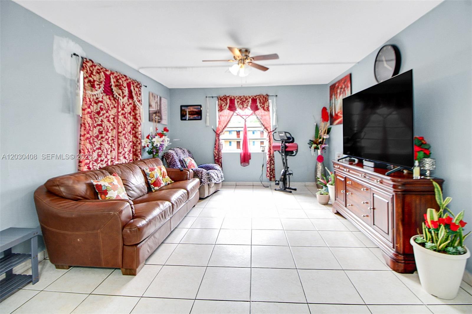 A living room features a brown leather sofa, a television on a wooden console, and tile flooring — 10745 SW 3rd St # 6, Sweetwater FL 33174, SWEETWATER, FL