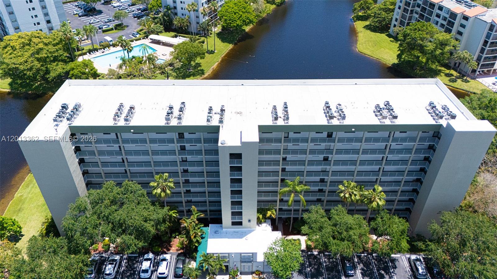 An aerial view shows a multi-story apartment building with a flat roof and parking lot — 2232 N Cypress Bend Dr # 507, Pompano Beach FL 33069, POMPANO BEACH, FL