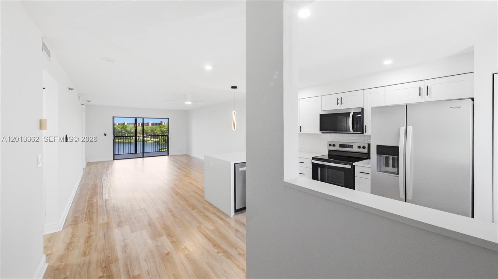 A bright kitchen with white cabinets overlooks an open living area with wood flooring — 2232 N Cypress Bend Dr # 507, Pompano Beach FL 33069, POMPANO BEACH, FL