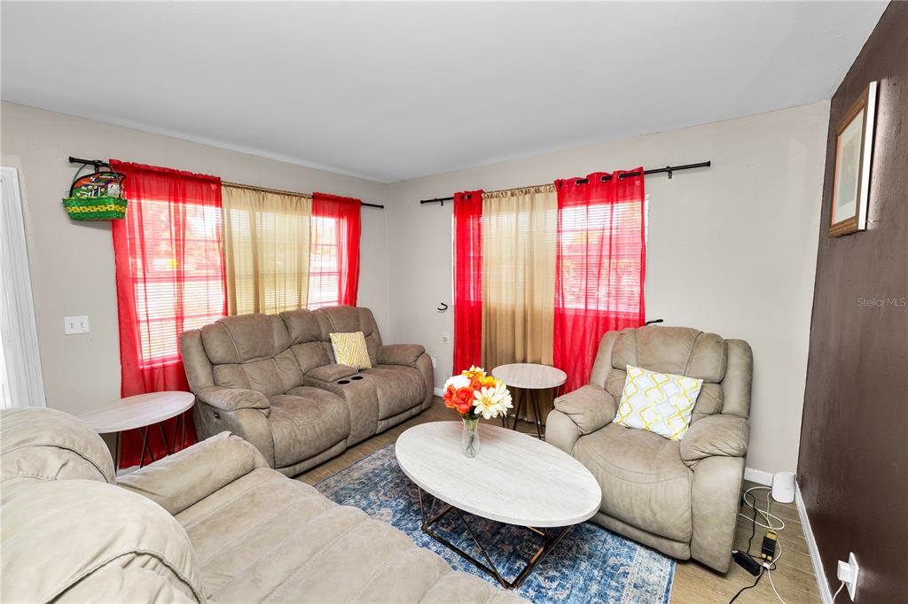 A living room features beige furniture, a blue patterned rug, and red and gold curtains — 300 AVENUE V NE, WINTER HAVEN, FL