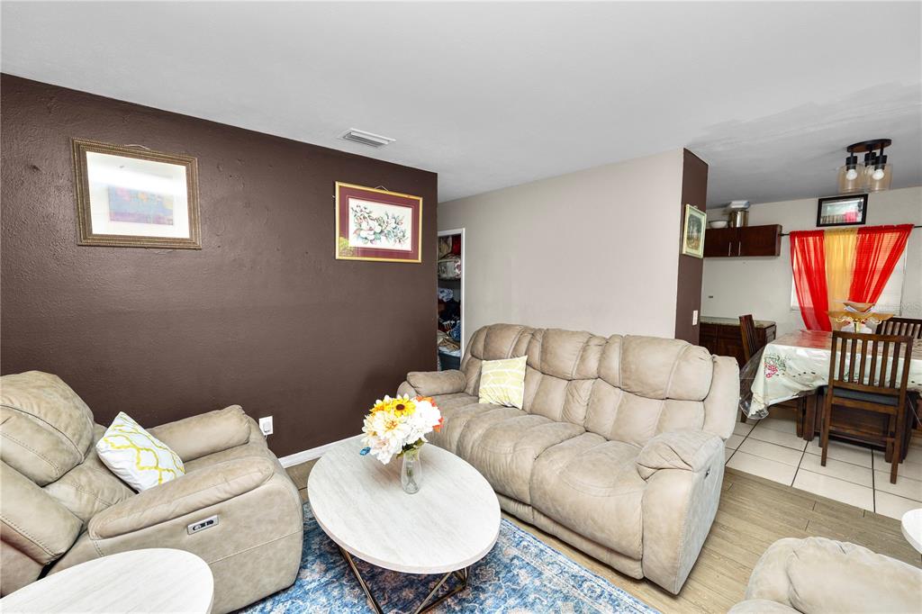 A living room with brown walls, light-colored reclining furniture, and an adjacent dining area — 300 AVENUE V NE, WINTER HAVEN, FL