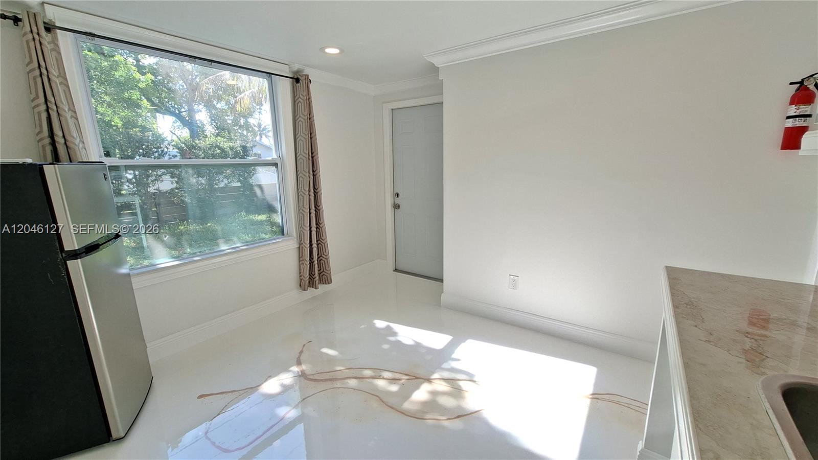A bright kitchen features white epoxy flooring, a large window, and a stainless steel refrigerator — 1028 S 62nd Ave # B, Hollywood FL 33023, HOLLYWOOD, FL