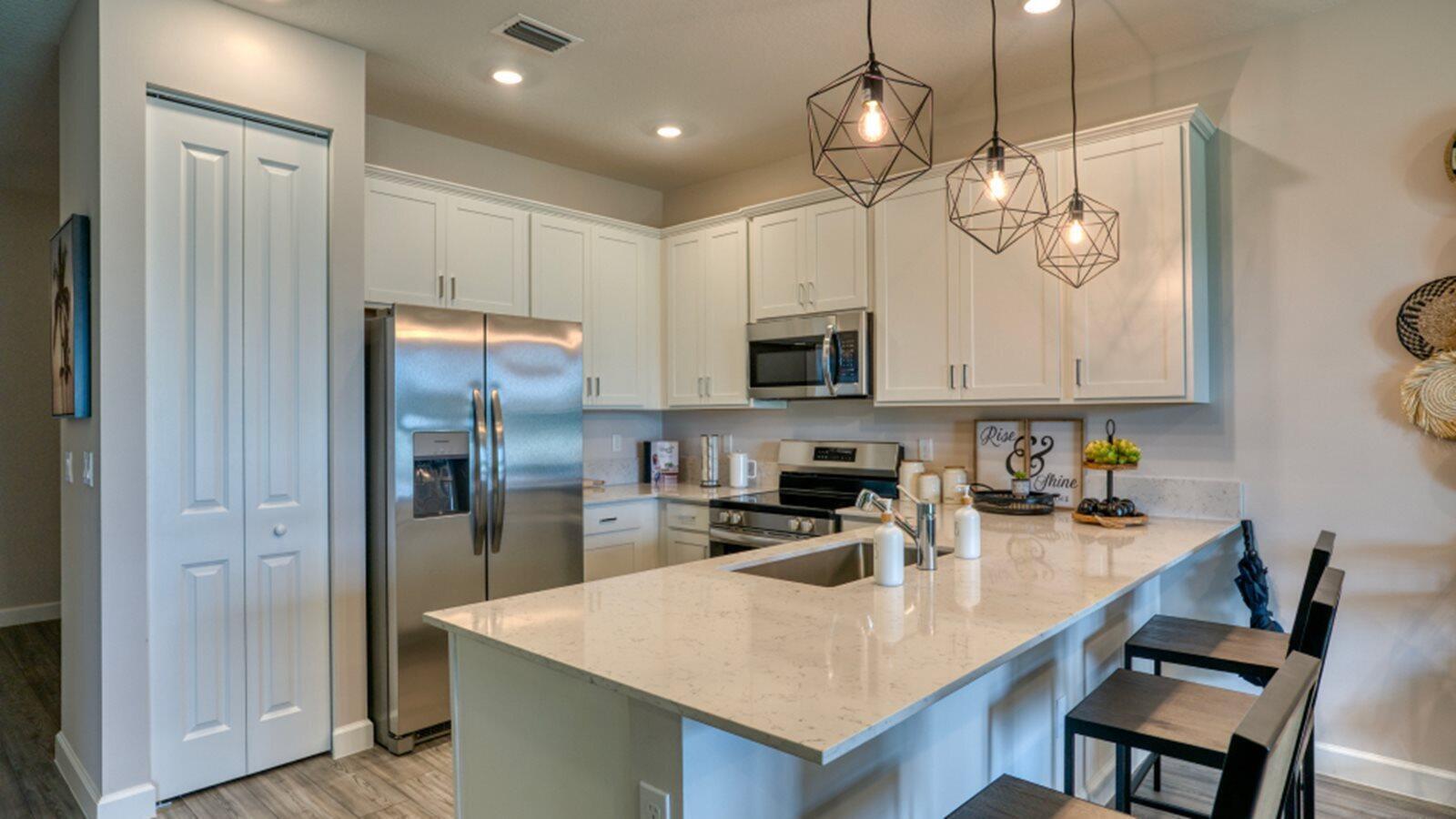 A kitchen features white cabinets, stainless steel appliances, a quartz countertop island, and pendant lighting — 3616 Spanish Cedar Place, Fort Pierce FL 34946, FORT PIERCE, FL