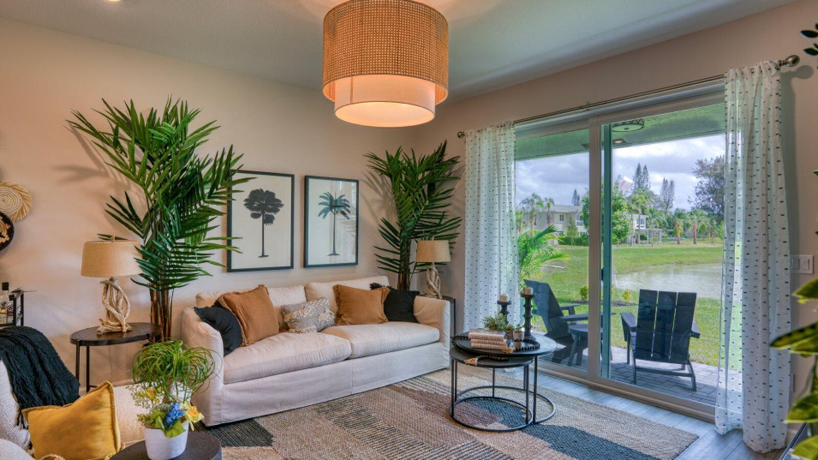 A living room features a sofa, two palm plants, a coffee table, and sliding glass doors — 3616 Spanish Cedar Place, Fort Pierce FL 34946, FORT PIERCE, FL
