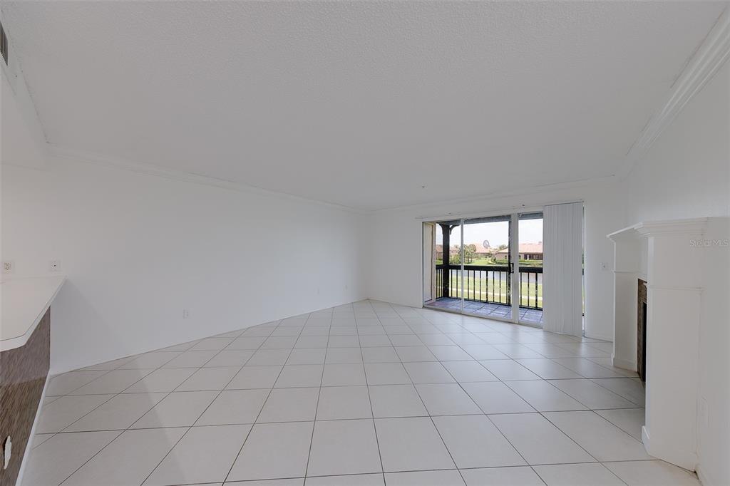 A bright living room features white tile floors, a fireplace, and sliding glass doors — 2400 FEATHER SOUND DRIVE UNIT 928, CLEARWATER, FL