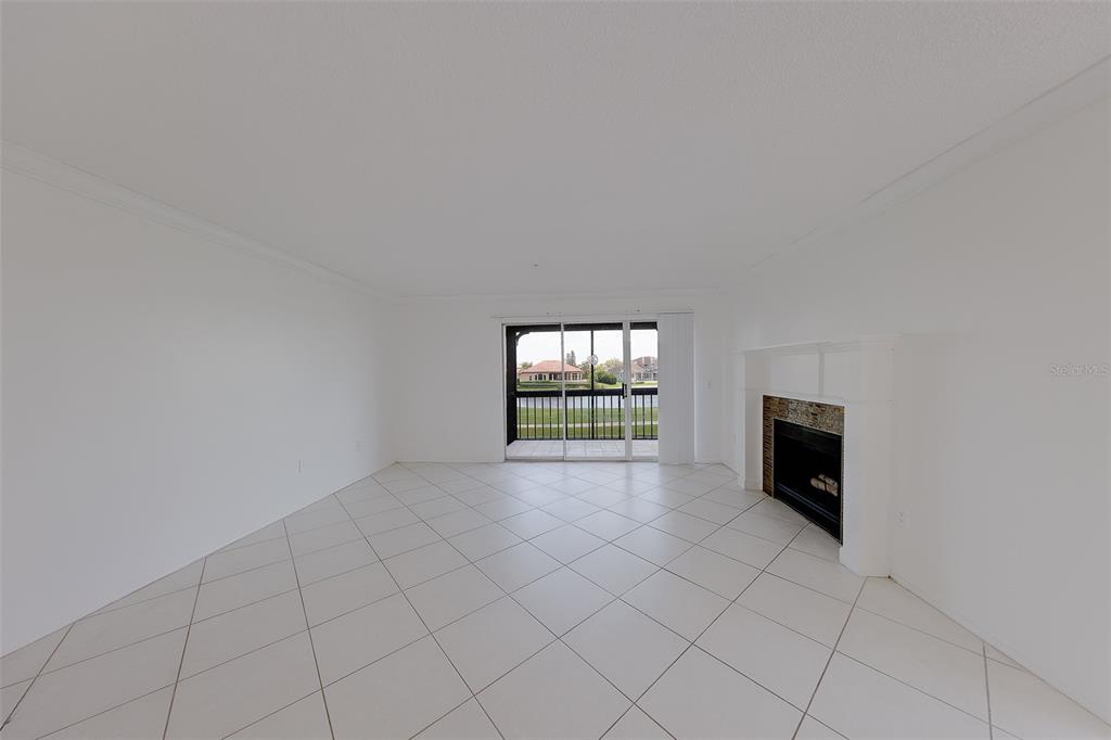 An empty living room features white tile floors, white walls, and a sliding glass door — 2400 FEATHER SOUND DRIVE UNIT 928, CLEARWATER, FL