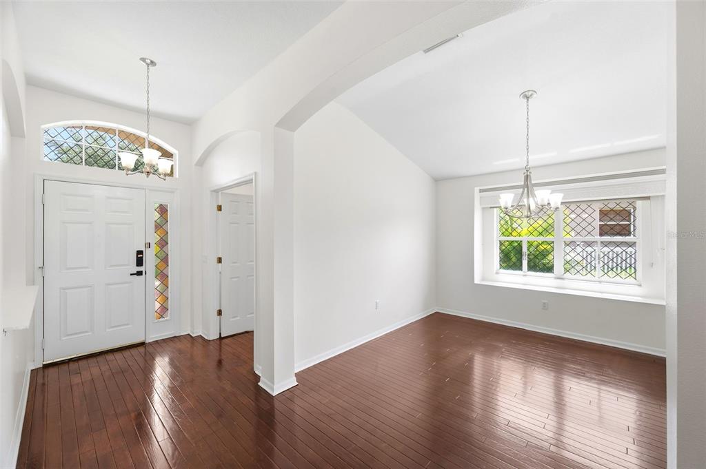 An entryway and dining area feature white walls, dark hardwood floors, and decorative window panes — 13510 GLOSSY IBIS PLACE, BRADENTON, FL