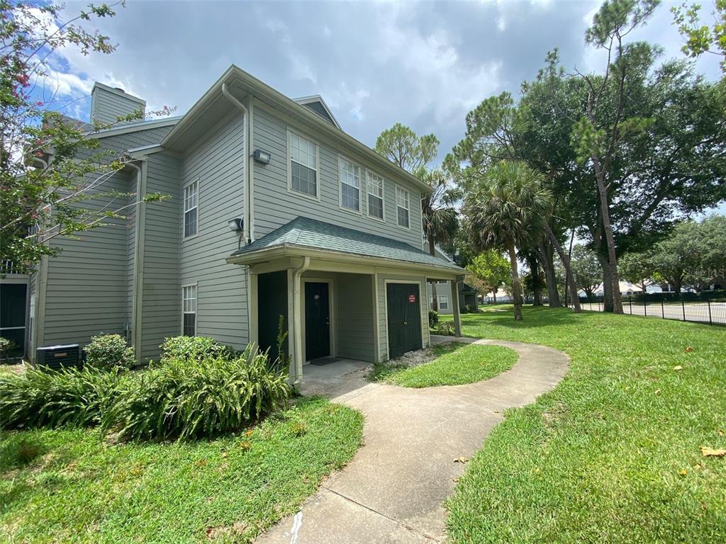 A two-story light green siding townhouse with a covered entryway and a concrete walkway — 6100 WESTGATE DRIVE UNIT 103, ORLANDO, FL
