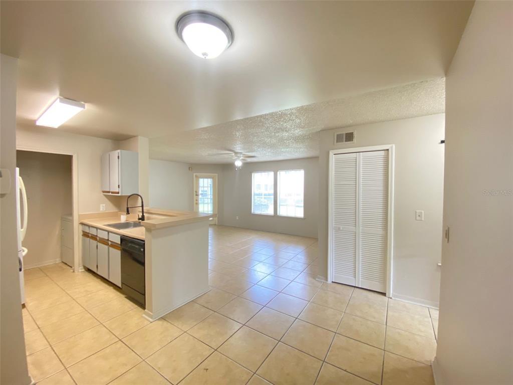 A kitchen with a breakfast bar opens into a living area with tiled floors — 6100 WESTGATE DRIVE UNIT 103, ORLANDO, FL