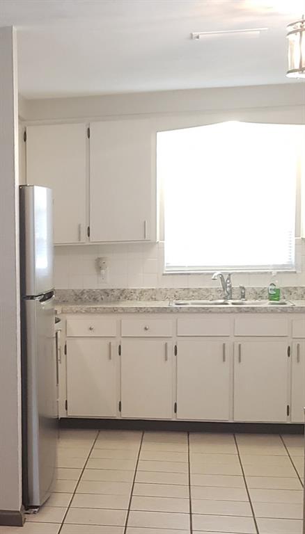 A kitchen with white cabinets, a stainless steel refrigerator, and light-colored tiled flooring — 5652 18TH STREET, ZEPHYRHILLS, FL