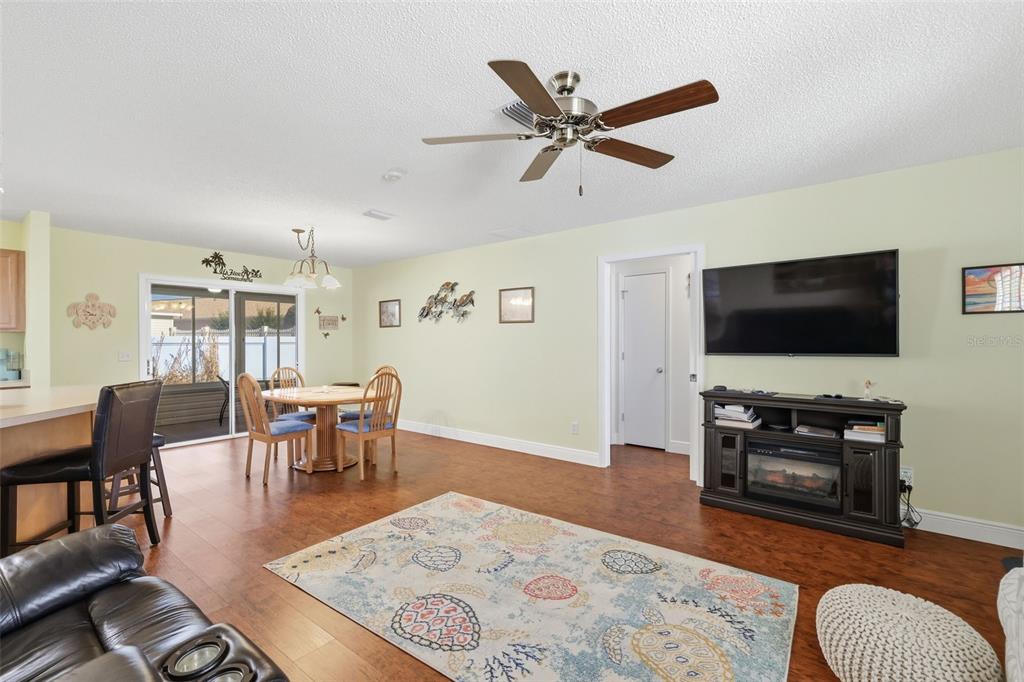 A living room with wood flooring, a ceiling fan, a dining area, and a television — 1609 BLOSSOM TERRACE, THE VILLAGES, FL