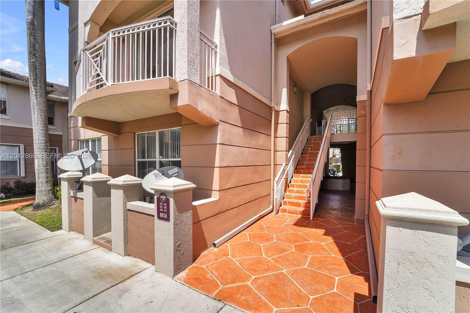 A multi-story apartment building features a parking lot with several cars in front — 8858 W Flagler St # 210, Miami FL 33174, MIAMI, FL