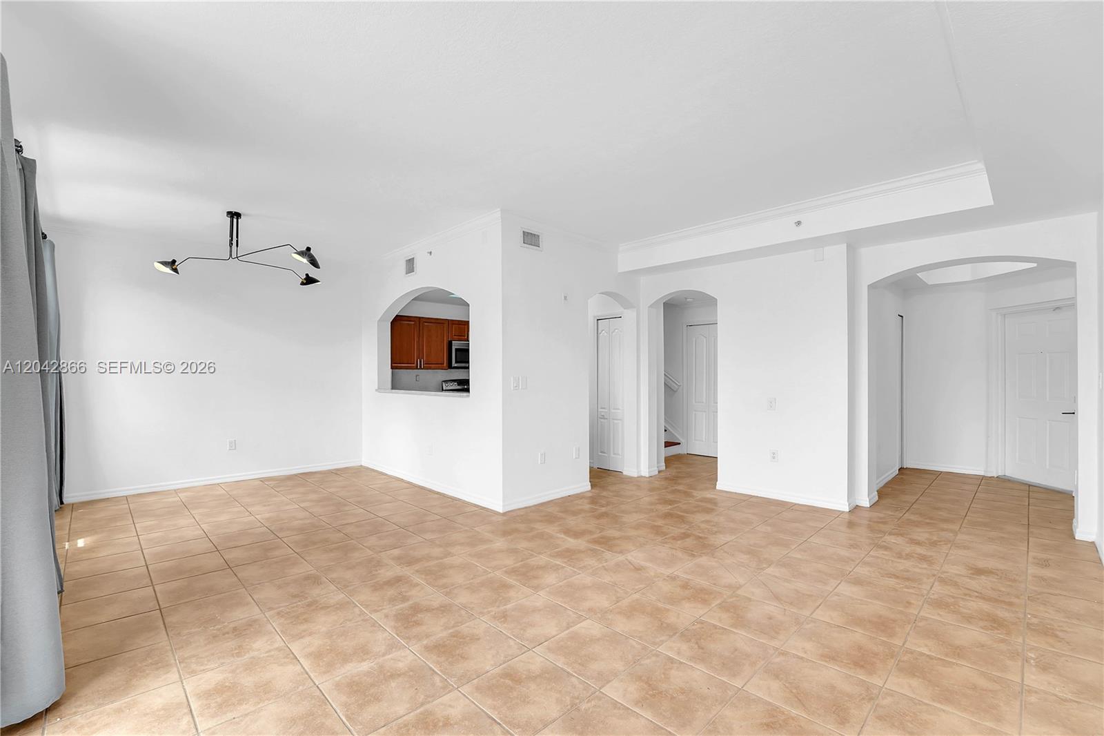 An open-concept living area features white walls, beige tile flooring, and a pass-through kitchen window — 8858 W Flagler St # 210, Miami FL 33174, MIAMI, FL