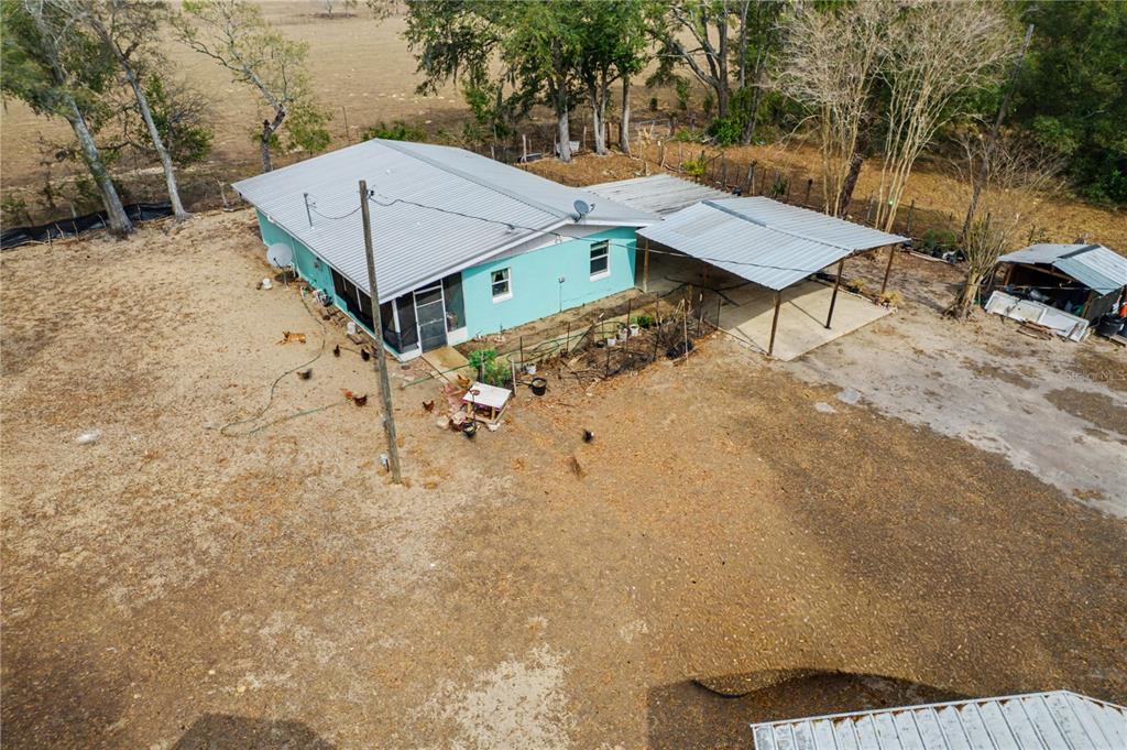 An aerial view shows a turquoise house with a metal roof and an attached carport — 5710 NE 140TH COURT, WILLISTON, FL