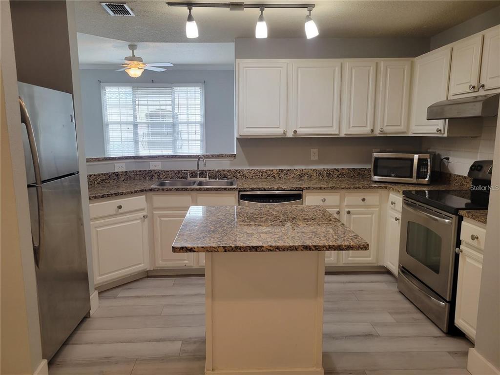 A kitchen with white cabinets, granite countertops, stainless steel appliances, and a central island — 501 KNIGHTS RUN AVENUE UNIT 1113, TAMPA, FL