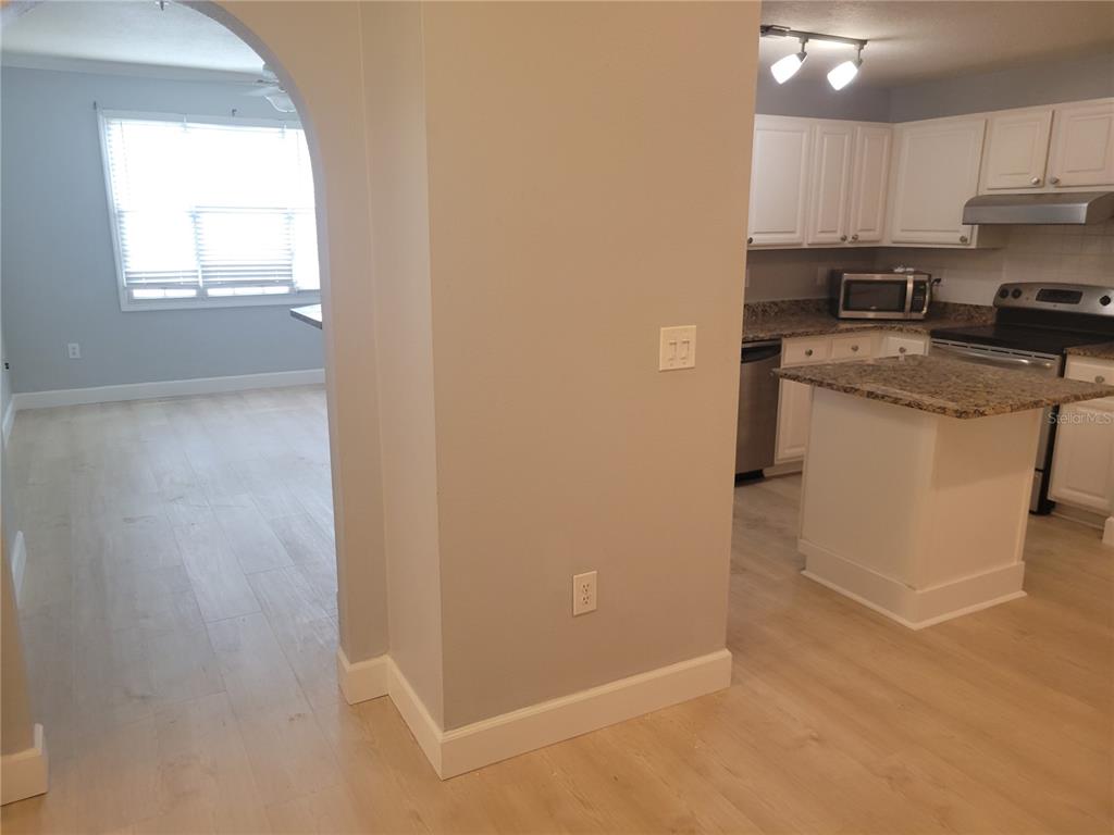 A kitchen with white cabinets and granite countertops is visible through an arched doorway — 501 KNIGHTS RUN AVENUE UNIT 1113, TAMPA, FL