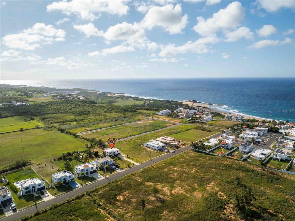 An aerial view shows a coastal neighborhood with modern houses near the ocean — 1893 AVENIDA MANUELA LAMELA ABREU, ISABELA, PR