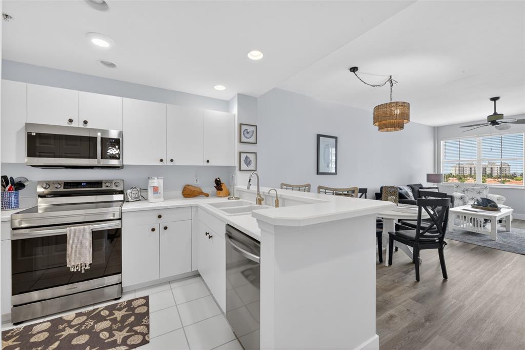 A white kitchen with stainless steel appliances opens to a dining and living area — 2090 MATECUMBE KEY ROAD UNIT 1603, PUNTA GORDA, FL