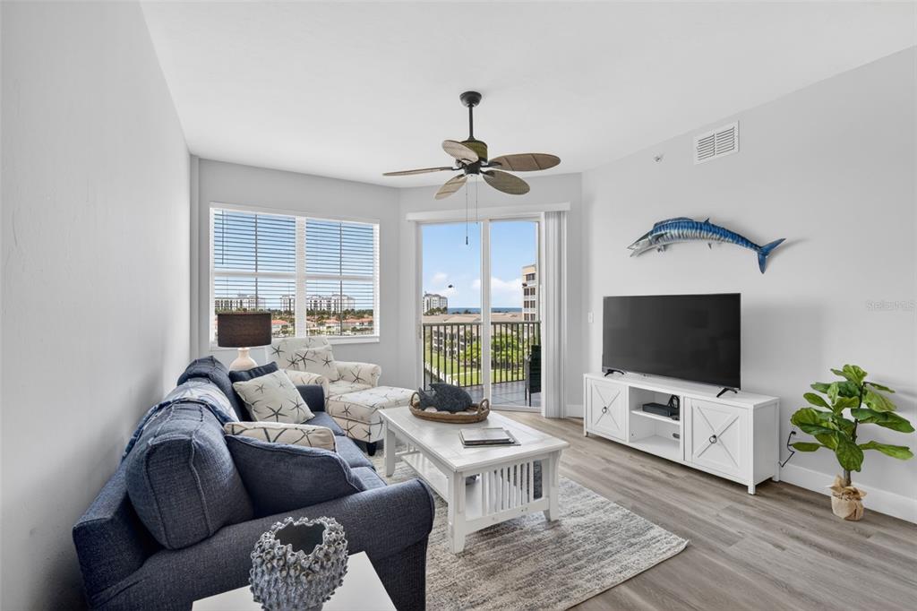 A living room features a blue sofa, white coffee table, television, and a balcony view — 2090 MATECUMBE KEY ROAD UNIT 1603, PUNTA GORDA, FL