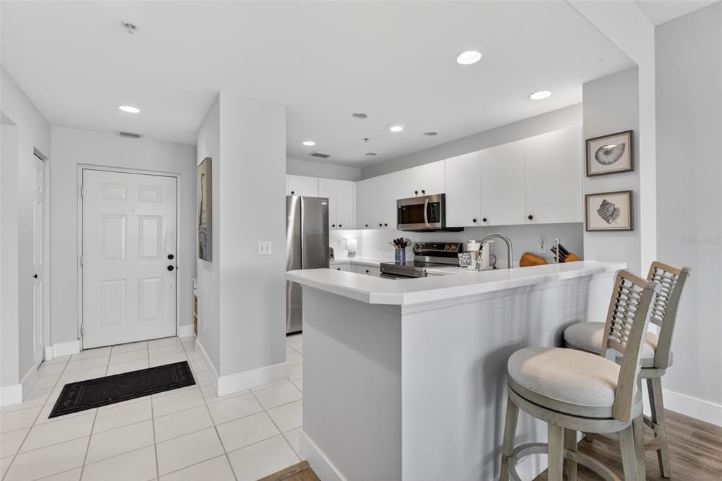 A kitchen features white cabinets, stainless steel appliances, a breakfast bar, and tiled flooring — 2090 MATECUMBE KEY ROAD UNIT 1603, PUNTA GORDA, FL