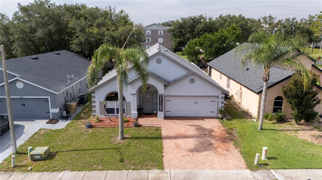 An aerial view of a single-story suburban house with a brick driveway and palm trees — 16404 COOPERS HAWK AVENUE, CLERMONT, FL